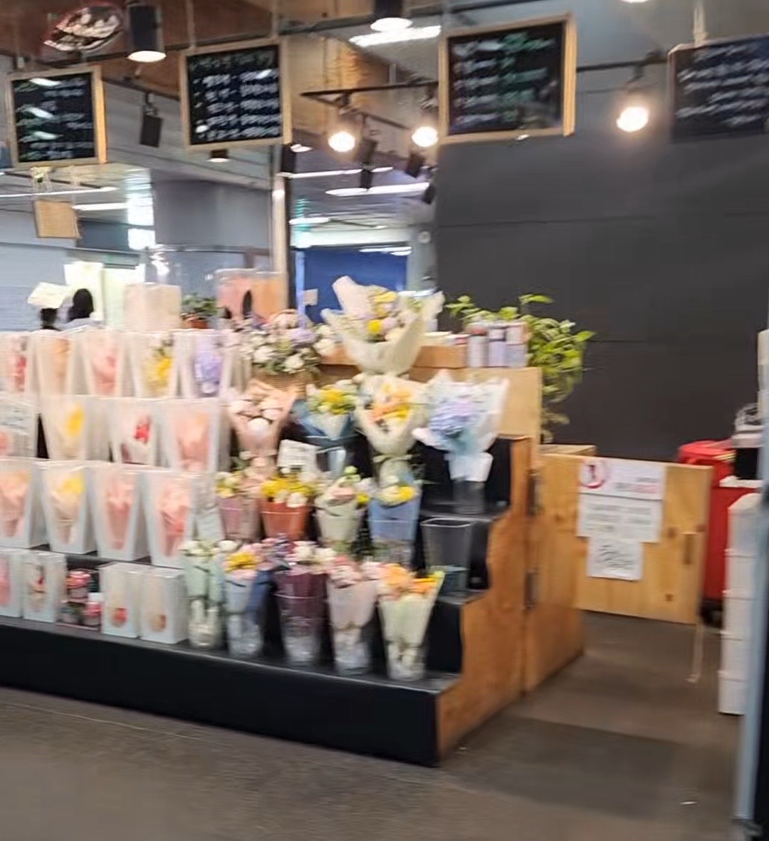 A flower stall inside Hongik Univ. Station, bouquets arranged on tiered shelving beside the walkway.