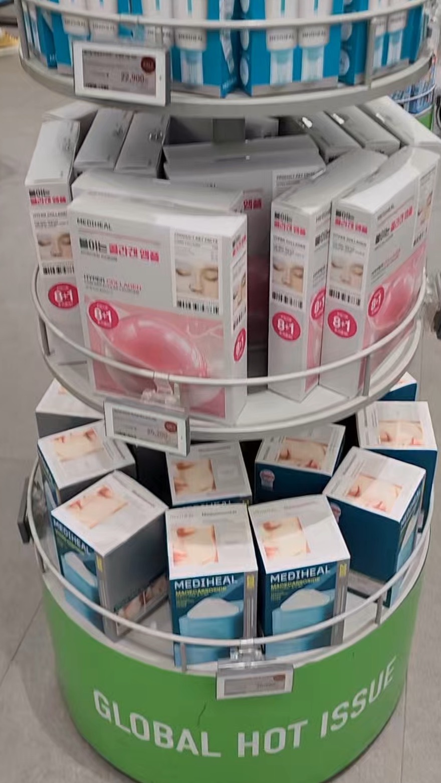 A tiered Olive Young display stand labelled GLOBAL HOT ISSUE, stacked with sheet masks and skincare boxes.
