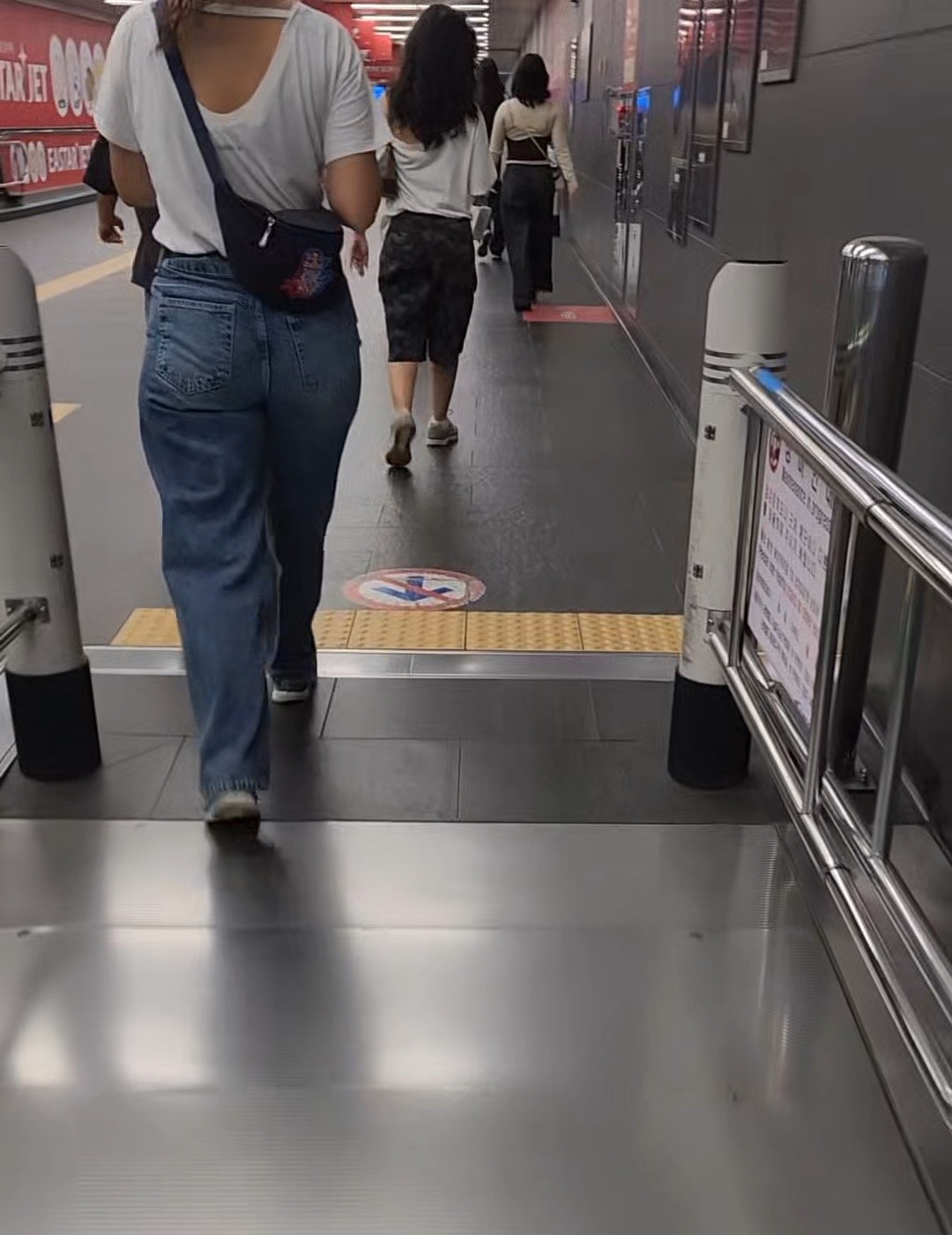 A moving walkway inside a Seoul subway station with passengers walking along it.